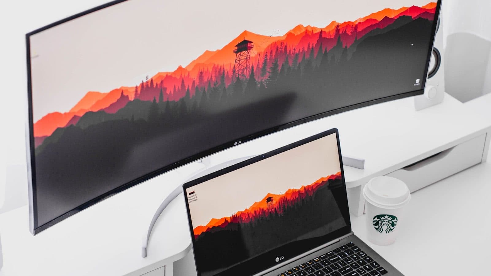 Zakrivljeni ultraširoki monitor i laptop na istom radnom stolu